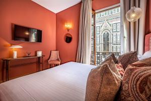 フィレンツェにあるホテル ドゥオモ フィレンツェのオレンジ色の壁のベッドルーム1室、窓付きのベッド1台が備わります。