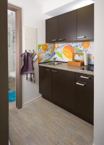 a kitchen with black cabinets and an orange wall at Apartment Magnolia in Karlstadt