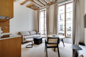 een keuken en een woonkamer met een bank en een tafel bij Pick A Flat's Apartments in Louvre - Rue Saint Honoré in Parijs