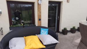 a wicker chair with three pillows on a patio at Wellness Ferienwohnung Biene im Bergischen Land in Much