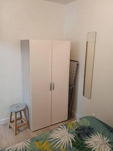 ein Schlafzimmer mit einem weißen Schrank und einem Stuhl in der Unterkunft Petit logement avec entrée indépendante 