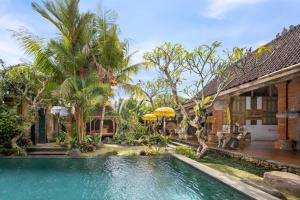 una piscina frente a una casa con palmeras en The Gardener's Cottage, en Ubud