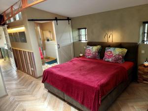 a bedroom with a large bed with a red blanket at De Ketse Steenuil in Kaatsheuvel