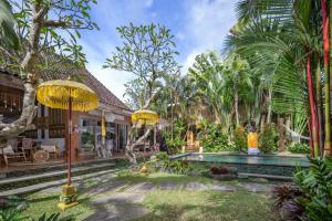 un patio con sombrillas amarillas y una piscina en The Gardener's Cottage, en Ubud