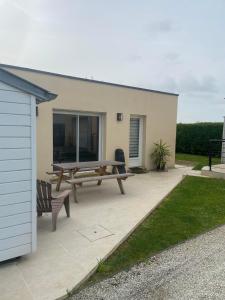 une terrasse avec une table de pique-nique et un banc dans l'établissement L'Ostréa, maison avec jardin à 200m de la mer-wifi, à Saint-Côme-de-Fresné