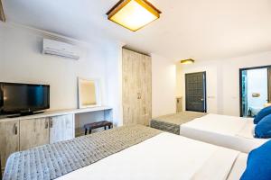 a hotel room with two beds and a flat screen tv at Costa Bodrum City in Bodrum City