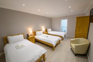 a hotel room with two beds and a chair at Ye Olde Plough House in East Horndon