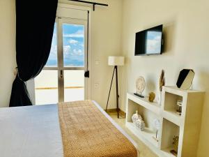 a bedroom with a bed and a tv and a window at LΟFT by Casa di Somnia in Lagoúdi Zía