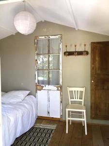 een slaapkamer met een bed, een stoel en een raam bij BASTIDON FARFALLINA in Puyvert
