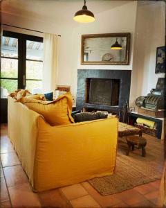 een gele bank in een woonkamer met een open haard bij BASTIDON FARFALLINA in Puyvert