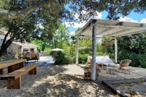 een paviljoen met een tafel en banken in een tuin bij BASTIDON FARFALLINA in Puyvert