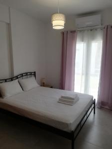een slaapkamer met een bed met witte lakens en roze gordijnen bij Brand new cozy apartment in Mesaíon Karlovásion