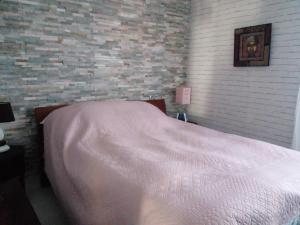 1 dormitorio con cama blanca y pared de ladrillo en Location zen en Provence, en Mormoiron