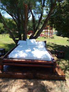 una cama sentada en una plataforma de madera bajo un árbol en Location zen en Provence, en Mormoiron