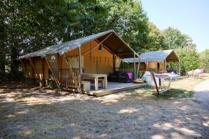 ein großes Gebäude mit einer Veranda und einem Zelt in der Unterkunft Glamping Vendée in Saint-Julien-des-Landes