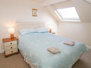 a bedroom with a bed with two towels on it at The Nook in Benllech