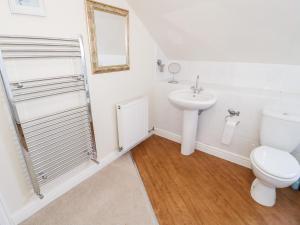 a white bathroom with a toilet and a sink at The Nook in Benllech +24 photos