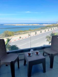 un balcón con 2 sillas y una mesa con 2 tazas en Studio avec vue directe mer en Monastir