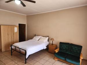 a bedroom with a bed and a green chair at Postmasburg Inn in Postmasburg +18 photos