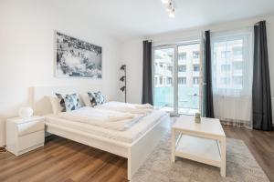 a white bedroom with a white bed and a window at White Cottage Studio in Budapest