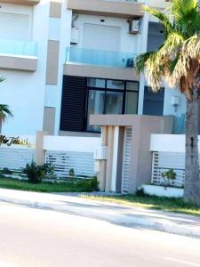 a building with a palm tree in front of a street at Studio avec vue directe mer in Monastir