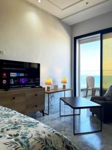 1 dormitorio con 1 cama, TV y mesa en Studio avec vue directe mer en Monastir