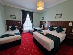 a hotel room with two beds and a red carpet at Lyndon Guesthouse in Dublin