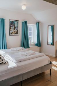 a bedroom with a large bed with blue curtains at KEFS Guesthouse & Café in Ærøskøbing