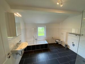 a bathroom with a sink and a tub and a toilet at Ferienhaus am Seedeich in Emden +19 photos