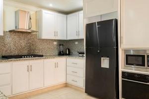 a kitchen with white cabinets and a black refrigerator at Villa Bayardo in San Felipe de Puerto Plata