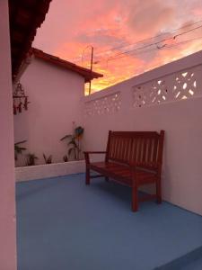 a wooden bench sitting on a balcony with a sunset at Pousada Recanto do Mar in Tutóia