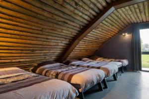 four beds in a room with a wooden wall at Koe in de Kost in Heeten