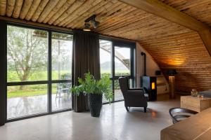 a living room with large windows and a table and a chair at Koe in de Kost in Heeten