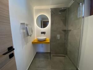 a bathroom with a sink and a shower with a mirror at Tomsan Suites & Villas Akyaka in Akyaka
