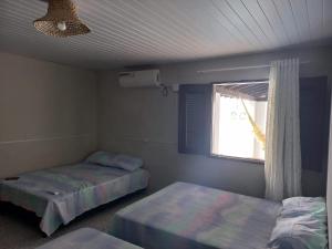 a room with two beds and a window in it at Pousada Recanto do Mar in Tutóia