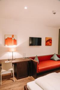 Zimmer mit einem roten Sofa und einem Schreibtisch in der Unterkunft Hotel Hofwirt Neubeuern in Neubeuern