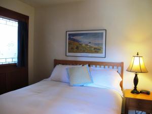 a bedroom with a white bed with a lamp and a picture at Harrison Street Inn in Cannon Beach