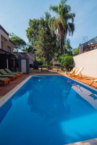 a large swimming pool with blue water in a yard at Palma Real Bungalow in Puerto Iguazú