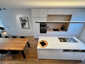 a kitchen with white cabinets and a wooden table at Ferias - cosy house in Bruges