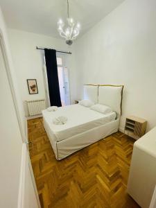 een slaapkamer met een wit bed en een houten vloer bij Central Suite in Rome