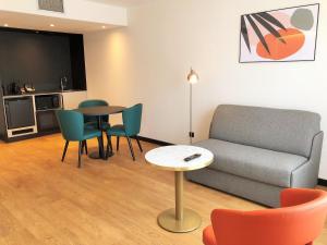 - un salon avec un canapé, une table et des chaises dans l'établissement Novotel Suites Montpellier Antigone, à Montpellier