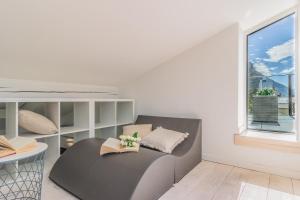a white room with a gray couch and a window at La terrazza di Marta in Varenna