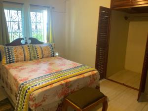 a bedroom with a bed and a window and a chair at POINCIANA APARTMENT ONE 257 POINCIANA DRIVE GREEN WOOD MONTEGO BAY JAMAICA in Montego Bay