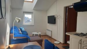 pequeña sala de estar con sofá azul y mesa en Apartamenty Delfin, en Gdansk