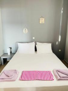 uma grande cama branca com toalhas cor-de-rosa e brancas em Seaside Deluxe Apartment em Skala Kallirachis