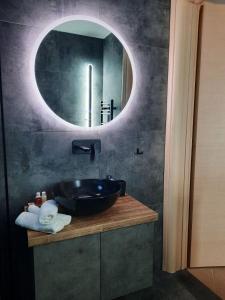 a bathroom with a sink and a round mirror at Seaside Deluxe Apartment in Skala Kallirakhis