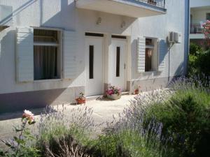 a white house with flowers in front of it at Grgin Apartments in Kaštela