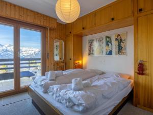 a bedroom with a bed and a large window at Apartment Muverans I L2 by Interhome in Nendaz