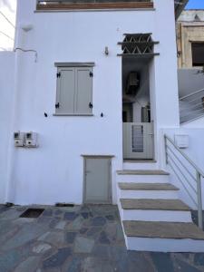 a white building with stairs and two windows at Marianna's Studio in Tinos