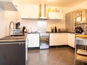 una cocina con armarios blancos y electrodomésticos negros en Holiday Home Au Romarin - BEF130 by Interhome, en Bagnols-en-Forêt
